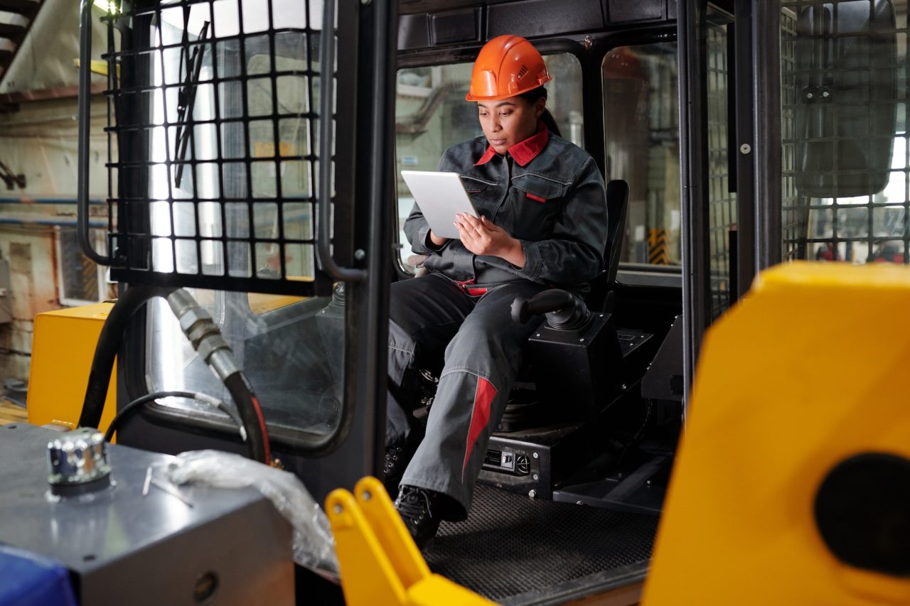 young busy worker of factory scrolling in tablet in construction machine.jpg